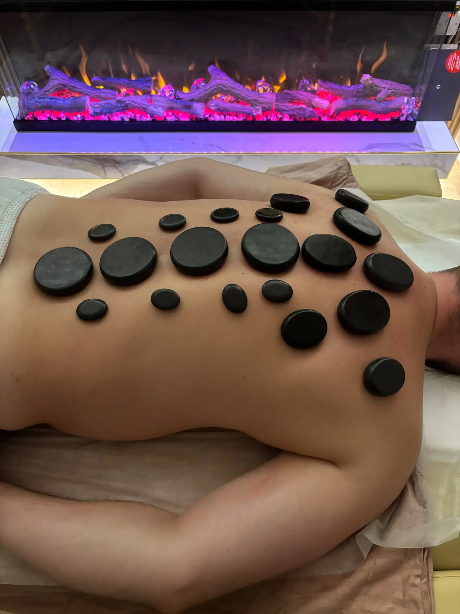 Warm stones arranged across a client's shoulders and upper back